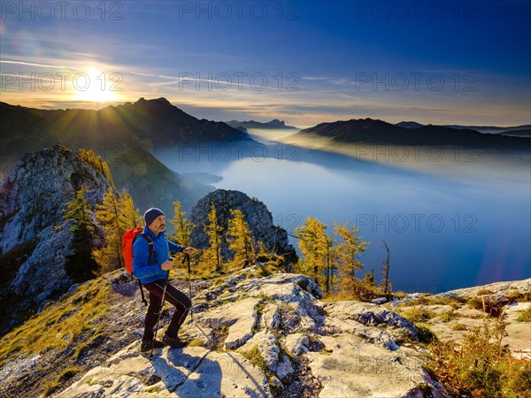 Mountaineer climbing the large Schoberstein in the evening light with view of Attersee and Mondsee