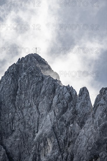 Rocky summit with summit cross between clouds