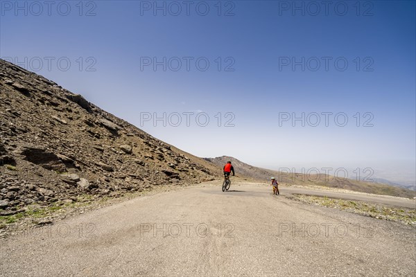 Professional cyclist speeding downhill and small boy biker struggling uphill in Sierra Nevada mountains