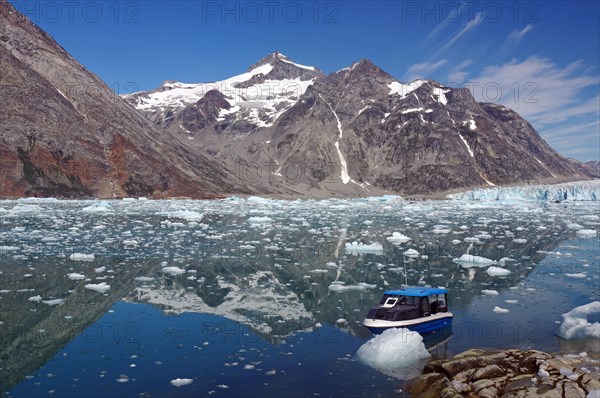 Small boat in a fjord with ice and icebergs