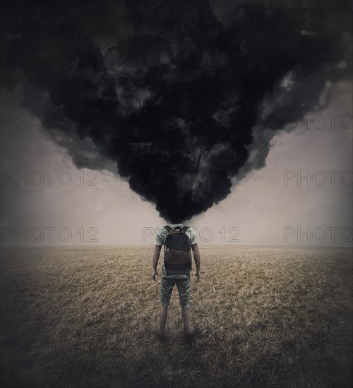 Surreal scene of a lone man in the field with dense black smoke instead his head