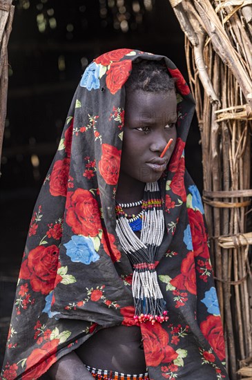 Traditional dressed child of the Jiye tribe sitting in her hut