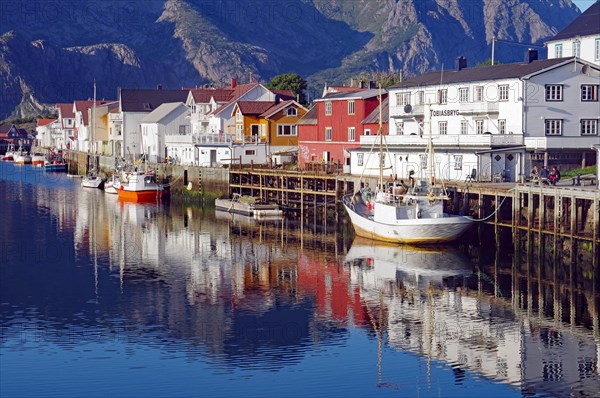 Fishing boats and houses reflected in the calm waters of a harbour