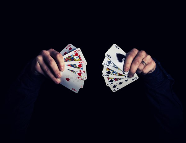 Man's hands holding five playing cards each over