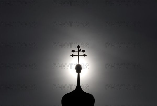 Double cross with dove on a church tower in backlight