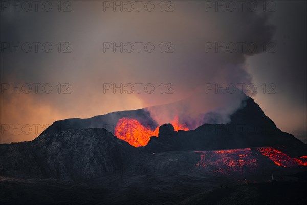 Erupting volcano with lava fountains and lava field