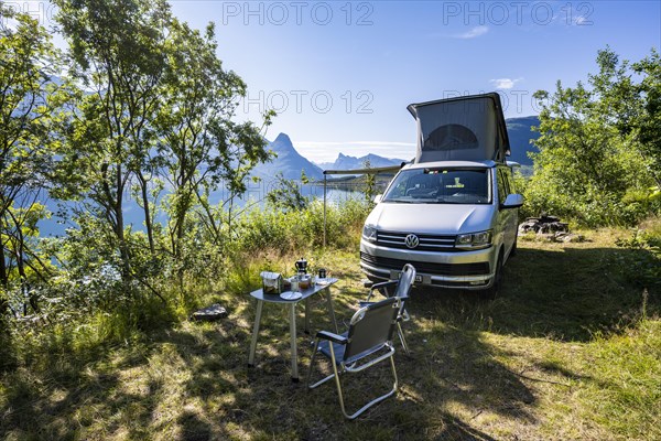 Camper standing by fjord with view of mountains