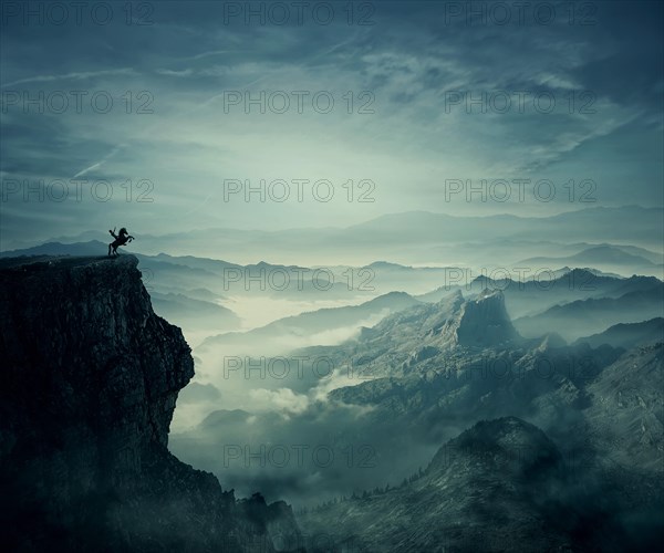 Young man riding a wild horse on the peak of a cliff