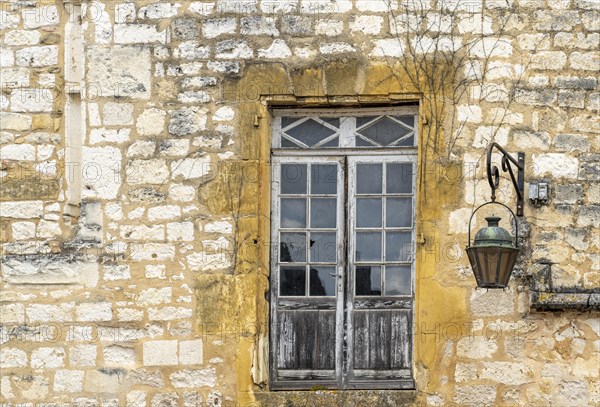 Window with old street lamp on an old house in the historic old town of Monpazier