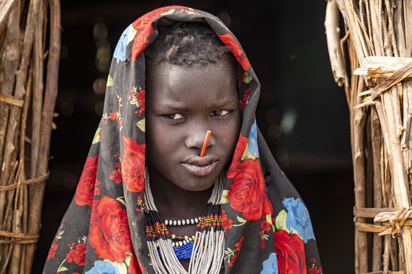 Traditional dressed child of the Jiye tribe sitting in her hut