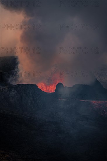 Erupting volcano with lava fountains and lava field