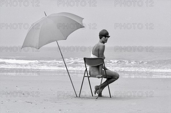 Woman with parasol on chair at the beach