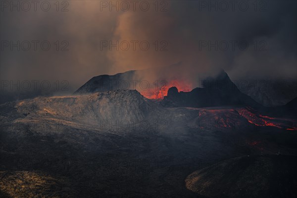 Erupting volcano with lava fountains and lava field