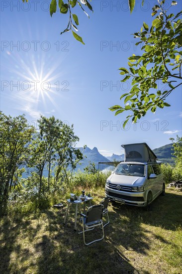 Camper standing by fjord with view of mountains