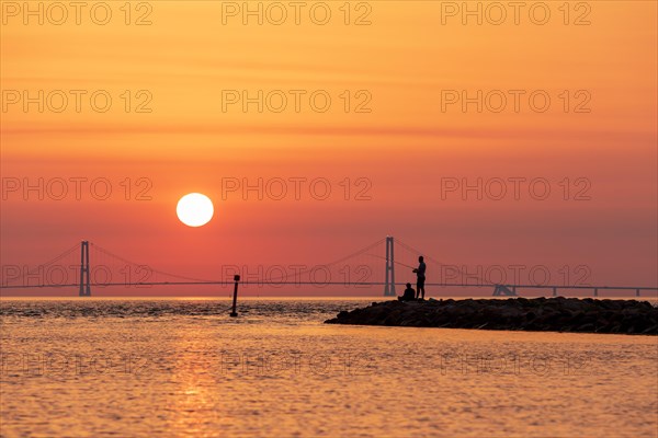 Silhouette of two men fishing with the Great Belt Bridge in the background