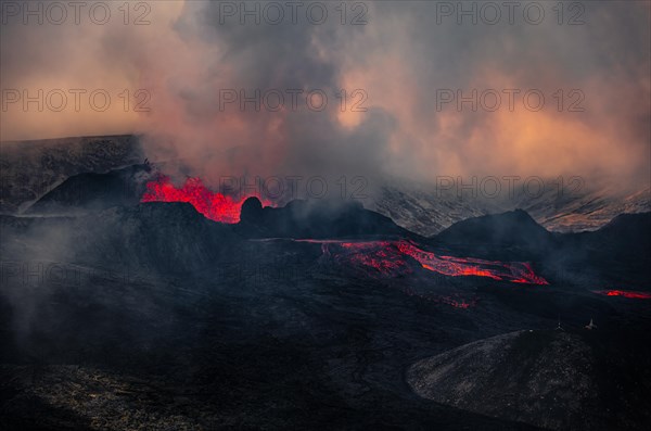 Erupting volcano with lava fountains and lava field