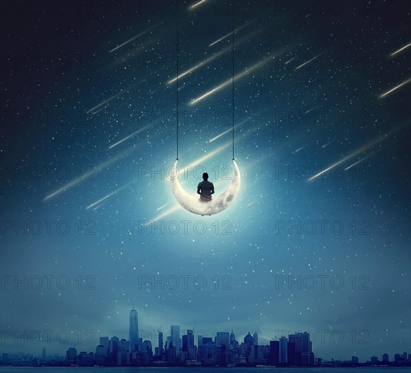 Surreal background with a boy sitting on a crescent moon