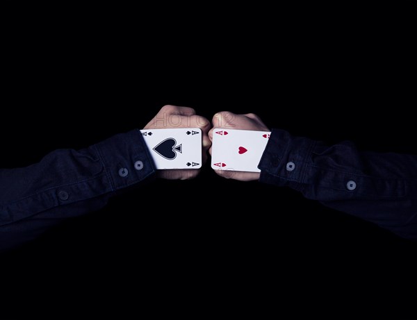 Two fists with hearts and spades aces against each other