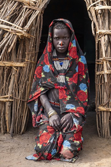 Traditional dressed child of the Jiye tribe sitting in her hut