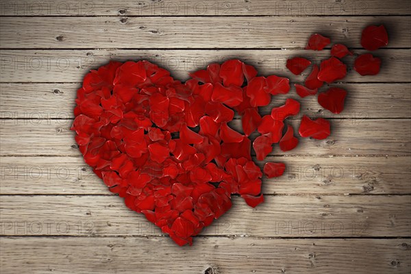 Red rose petals arranged in shape of a broken heart on wooden table