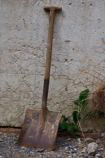 Old shovel leaning against house wall
