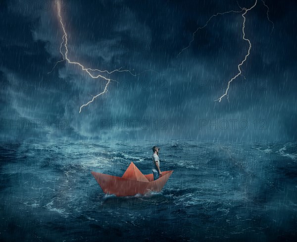 Young boy in a orange paper boat sail lost in the ocean