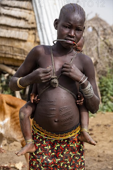 Scar face and body as a mark of beauty woman from the Jiye tribe sitting in her hut