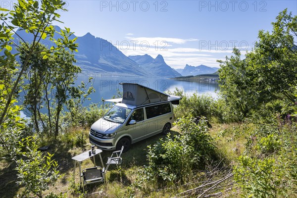 Camper standing by fjord with view of mountains