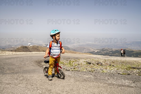 Small boy riding uphill on his first bicycle in Sierra Nevada mountains