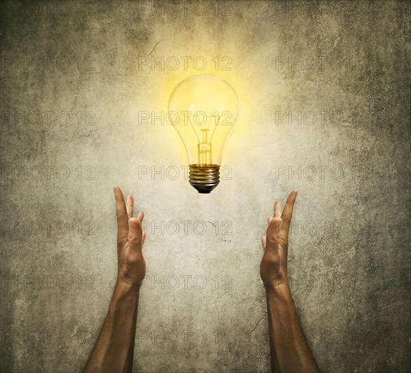 Closeup of two human hands holding a light bulb