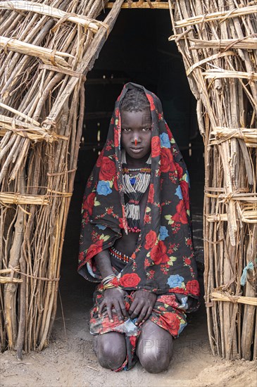 Traditional dressed child of the Jiye tribe sitting in her hut