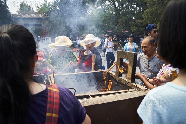 Tourists with incense sticks at the Llama Temple