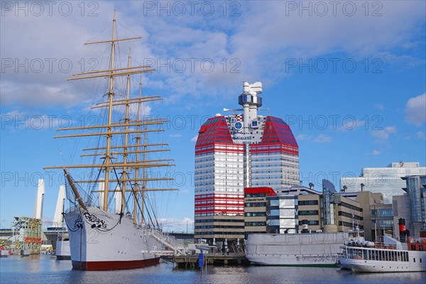 Sailing ship and other ships in front of a red skyscraper