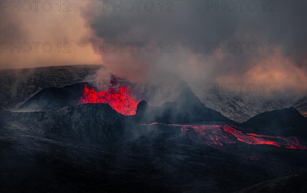 Erupting volcano with lava fountains and lava field