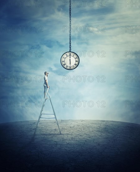 Young boy stay on the top of a ladder in the middle of a cracked desert ground