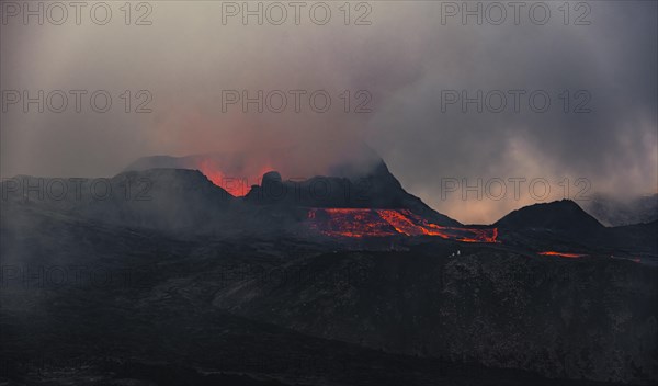 Erupting volcano with lava fountains and lava field