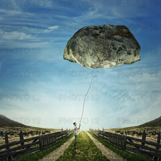 Surrealistic image as a young boy stand on a country road