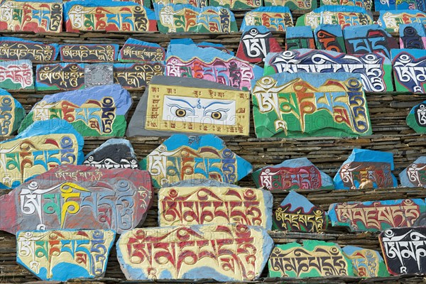 Huge piled up mountain of mani stones with Tibetan writing at a Tibetan monastery in the grasslands of Tagong