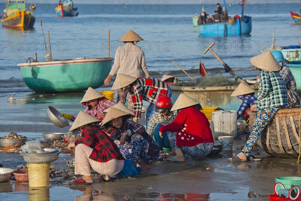 Women with straw hats on the beach with freshly caught fish and seafood