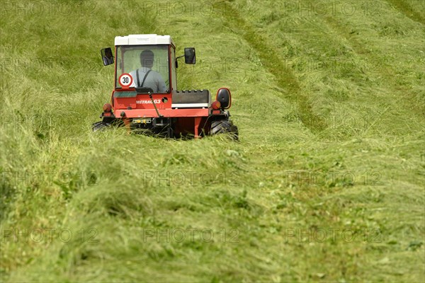 Farmer cutting grass with a tractor