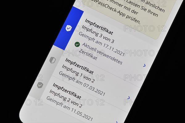 Symbolic photo App CovPass on smartphone with digital European vaccination certificate after third booster vaccination against Covid-19