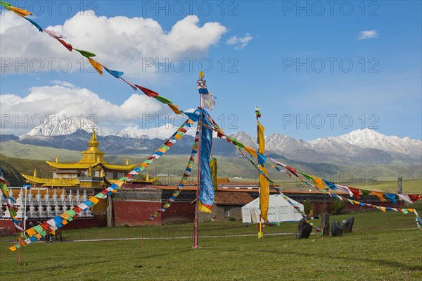 Golden roofs and chorten of a Tibetan monastery in the grassland of Tagong in front of Mount Zhara Lhatse