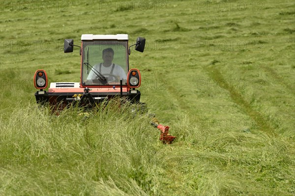 Farmer cutting grass with a tractor