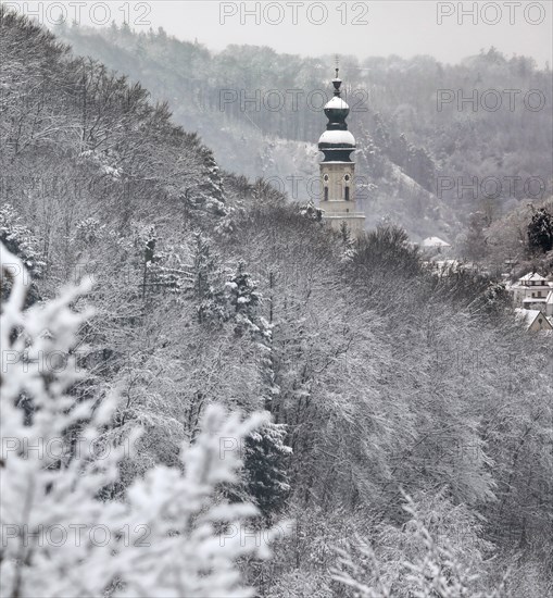 Church tower overlooks snowy winter forest in Salzach valley