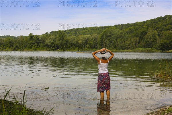 Woman with sun hat and skirt standing in the water
