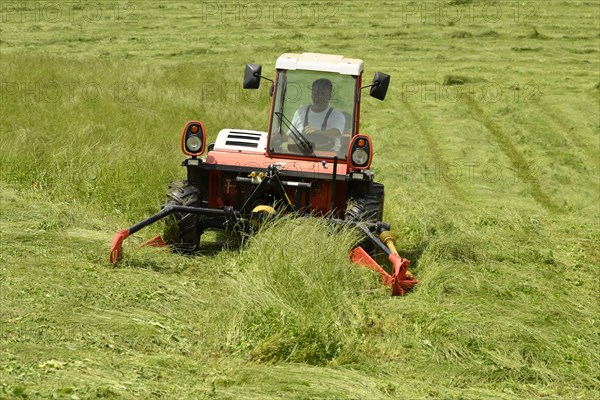 Farmer cutting grass with a tractor