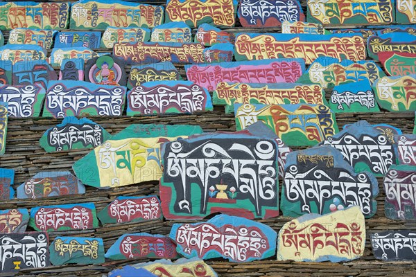 Huge piled up mountain of mani stones with Tibetan writing at a Tibetan monastery in the grasslands of Tagong