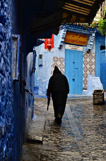 Old man in alley carrying umbrella after drizzle