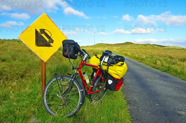 Bicycle in front of road sign warning of steep gradient