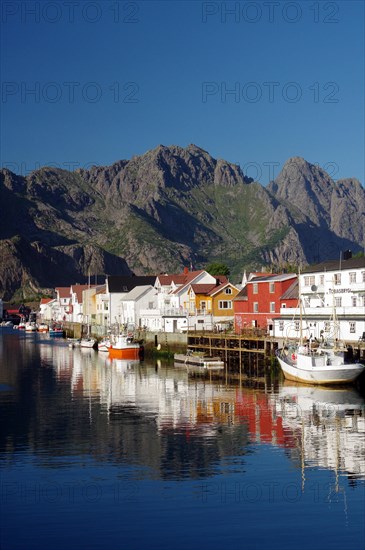 Fishing boats and houses reflected in the calm waters of a harbour